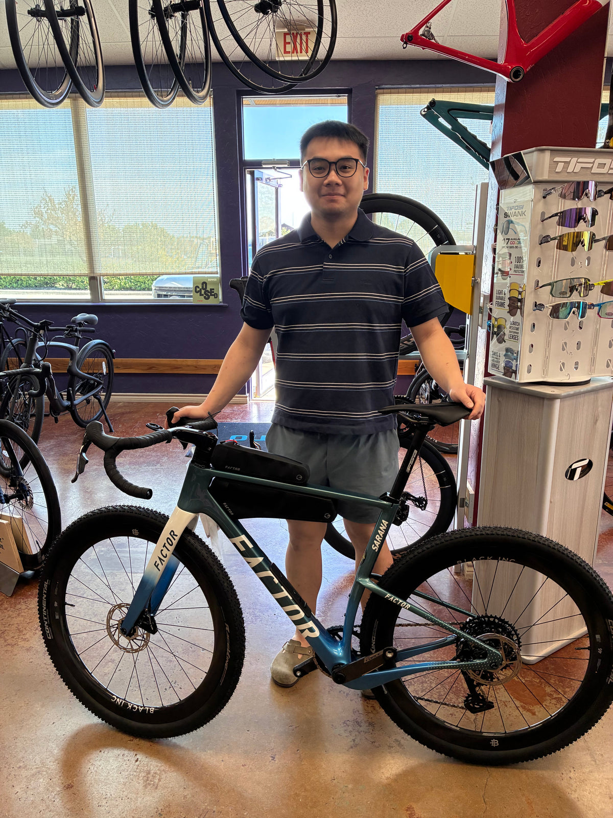 Rider with a Factor SARANA gravel bike and frame bags inside Mad Duck Cyclery